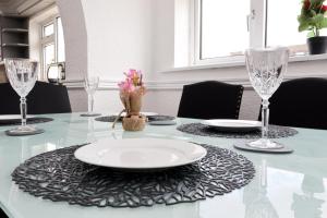 a dining room table with a white plate and glasses at King Beds - Dining Space - Ev Charger - Coffee - Contractor & Families in Coity +25 photos