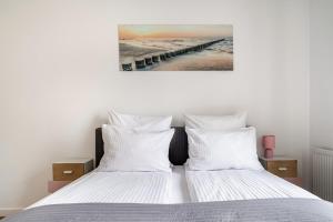 een bed met witte lakens en een foto van een pier bij MiCasaEsSuCasa with free parking! in Gdańsk