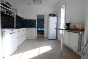 a kitchen with white cabinets and a white refrigerator at Maison cosy avec jardin proche plage et forêt in Grand-Village-Plage +4 photos