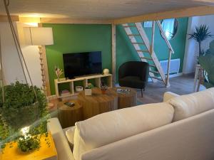 a living room with a white couch and a tv at Le nid d'Ambre in Étaples