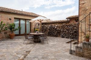 eine Terrasse mit Tisch und Stühlen und einem Sonnenschirm in der Unterkunft Country House Podere I Prati in Chianciano Terme