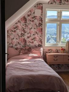 a bedroom with a bed with pink floral wallpaper at Bellahuset - Charming House in Ulsteinvik in Ulsteinvik