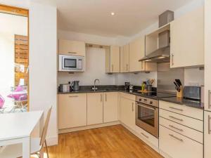 a kitchen with white cabinets and a sink and a table at Pass the Keys Oxford Castle - City Centre Apartment Balcony in Oxford