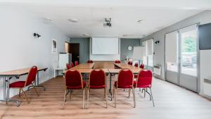a conference room with a table and red chairs at Campanile NATURE - Thionville Yutz in Basse-Yutz