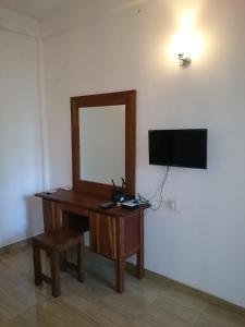 a desk with a mirror and a television on a wall at Isanka Lion Lodge in Sigiriya