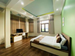 Tân UyênにあるTriệu Nguyễn Hotelのベッドと机とテレビのある寝室 +18枚の写真