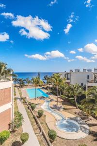 a view of a swimming pool with palm trees and the ocean at Skyline Azur - Luxueux Penthouse Front de Mer in Flic-en-Flac