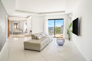 a living room with a couch and a tv at Skyline Azur - Luxueux Penthouse Front de Mer in Flic-en-Flac