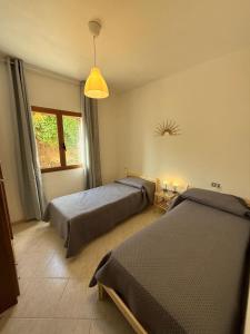 a bedroom with two beds and a window at Isola Rossa Appartamenti Comfort plus in Isola Rossa