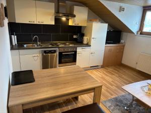 a kitchen with white cabinets and a wooden table at Ferienwohnungen Schellein in Blaibach
