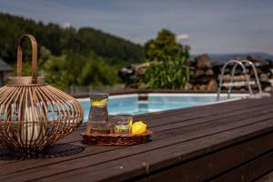 a table with a vase and two glasses on a table with a pool at CHATA POD PRZEHYBĄ in Stary Sącz