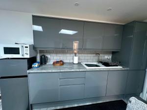a kitchen with gray cabinets and a white microwave at Home Away From Home in Blean