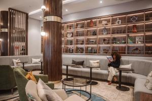 a woman sitting on a couch in a waiting room at Radisson Hotel Cape Town Foreshore in Cape Town +109 photos