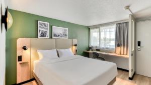 a bedroom with a white bed and a green wall at Campanile PRIME - Montpellier Est Le Millénaire in Montpellier