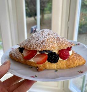 a person holding a sandwich with fruit on a plate at Caterina.C B&B in Val Della Torre