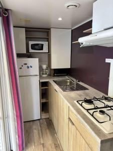 a small kitchen with a stove and a refrigerator at CAMPING 4 etoiles 3 Chambres in Mimizan-Plage