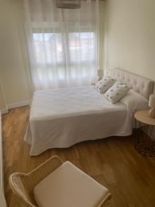 a bedroom with a large white bed and a window at Piso acogedor Rías Baixas in Meaño