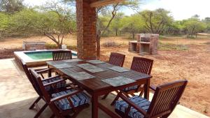 a wooden table and chairs on a patio with a pool at Vachellia View in Marloth Park