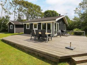 eine Holzterrasse mit einem Tisch und Stühlen darauf in der Unterkunft 6 person holiday home in Slagelse in Slagelse
