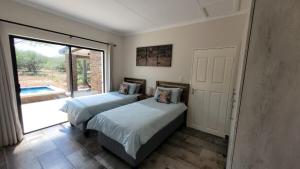 two beds in a room with a sliding glass door at Vachellia View in Marloth Park