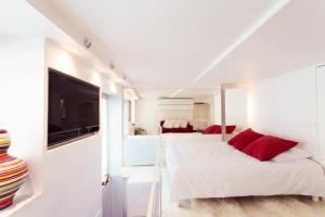 Stylish,luxury duplex Paris city center في باريس: غرفة نوم بسرير ومخدات حمراء وتلفزيون