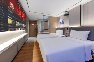 two beds in a hotel room with a wall at Dongguan Fenggang Weiduo Hotel in Tiantangwei +1 photo