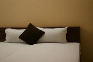 a bed with a black pillow and two white pillows at Hotel Krishna in Jaipur