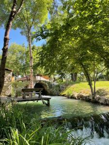una panchina di legno seduta su un ponte sopra un fiume di Moulin de Maris - Séjour détente a Saint-Cyprien