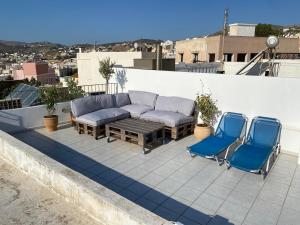 a patio with two chairs and a couch on a roof at Syra & Hermes Home in Ermoupoli