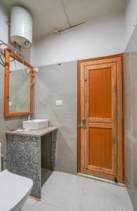 Un baño con puerta de madera y lavabo. en Deva's Retreat, en Jyotirmath