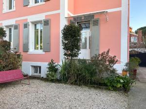 a pink house with a red bench in front of it at Petit Appartement dans une maison in Bayonne