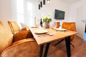 a dining room with a wooden table and leather chairs at Aesten Mare Kühlungsborn Apartment 2 in Kühlungsborn