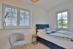 a bedroom with a bed and a chair and windows at Haus Oberdeck 2 in Scharbeutz
