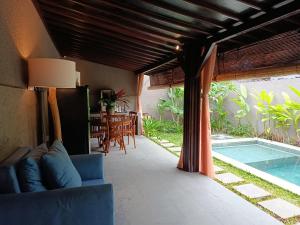 Una sala de estar con un sofá y una piscina. en Victory Beloved House Sanur Private Rooms Villa Bali, en Sanur
