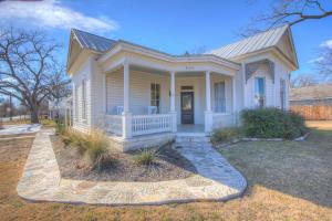 ein kleines weißes Haus mit einer Veranda und einer Einfahrt in der Unterkunft Gorgeous Home 1 Blk from Main with Hot Tub & Fire Pit! in Fredericksburg