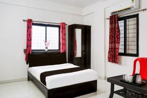 a bedroom with a bed and a window with red curtains at Super Hotel O Manjari Road in Mundhwa