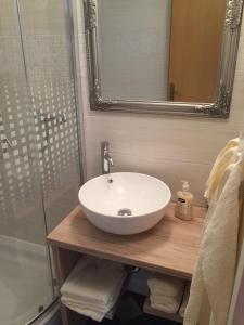La salle de bains est pourvue d'un lavabo blanc et d'une douche. dans l'établissement Titius Apartment, à Skradin