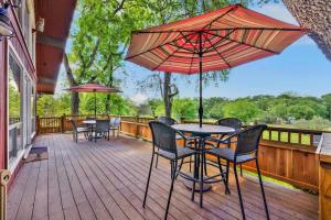 a deck with tables and chairs and an umbrella at Gettin' Guada loopy with Hot Tub & Riverfront in Schumannsville