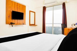 a bedroom with a white bed and a tv at Super Townhouse Lohegaon Near Pune Airport formerly Landmark Regency in Pune