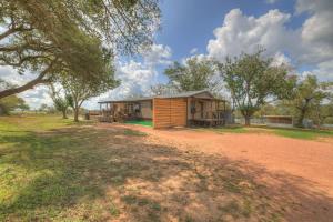 a small wooden cabin in a field with trees at Sage: Peaceful Hill Country Retreat with Hot-Tub! in Morris Ranch