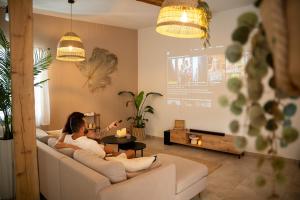 a woman sitting on a couch in a living room at La Villa Lova - Loveroom avec spa privatif à Pamiers in Pamiers