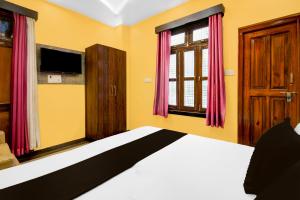 a bedroom with a bed and a tv and windows at Super OYO Hotel O Amhat Sultanpur City in Sultānpur