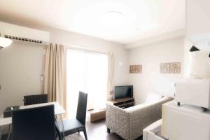 a living room with a couch and chairs and a television at 読谷波平2ベッドルームアパート海辺近く in Yomitan