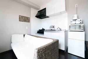 a living room with a couch and a kitchen at 読谷波平2ベッドルームアパート海辺近く in Yomitan