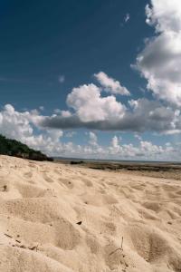 a sandy beach with a blue sky and clouds at 読谷波平2ベッドルームアパート海辺近く in Yomitan