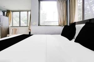 a white bed with black pillows in a room with windows at Super Collection O Andheri Near Mumbai Airport Formerly We Stay in Mumbai