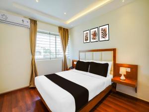 a bedroom with a white and black bed and a window at Super Townhouse Ramamurthy Nagar West Formerly Phoenix Hotel in Bangalore