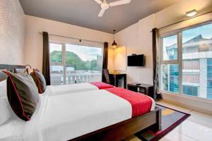 a bedroom with a bed and a large window at Super Townhouse Ulsoor in Bengaluru
