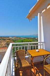 a wooden table and chairs on a balcony with the ocean at Lisa's Place in Elafonisos