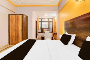 a bedroom with a white bed with a wooden headboard at Super Hotel O Insaf Nagar Munshipuliya Formerly Vibrant in Lucknow +35 photos